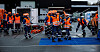 Redningsmannskaper i oransje verneklær øver med tau og utstyr på et avsperret område.