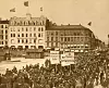 Dette bildet ble tatt på Youngstorget 1. mai 1908. I bakgrunnen ser vi det nye Folkets Hus. Parolene: 8 Timers Arbeidsdag - Arbeidere forener Eder - Bort med Overtidsarbeidet.