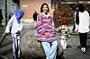 Flere barn på Tøyen som er ute på sparkesyklene sine, flokker seg rundt henne mens fotografen tar bilder. Hun smiler til dem.