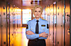Lise Sannerud i lyseblå uniform står med armene i kors i en korridor.