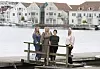 Fire ansatte fra Farsund barnevernstjeneste står på en brygge foran vannet og hvite trehus.