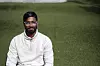 Shivaram Sivasubramaniam sitter på en grønn gressplen iført hvit genser og briller.
