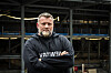 Oleg Grygoriuk står med korslagte armer foran en industriell havnekonstruksjon.