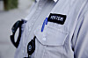 Nærbilde av lys vekteruniform med merket «VEKTER» og kontrollutstyr.