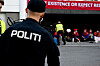 Politibetjent i forgrunnen mens demonstranter sitter samlet under en Fosen-protest.