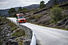 Rød Skyss-buss på en smal, svingete vei gjennom et steinete fjellandskap i Solund.