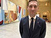 Andreas Bjelland Eriksen i mørk dress foran kunstverk og en rikt dekorert sal.