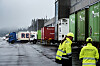 Containere og lastebiler på en våt terminal.