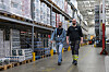 Tomasz Kapica og Sindre Mortensen går mellom høye pallereoler på Coops lager i Tromsø.