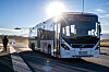 Tide-buss på holdeplass i Tromsø med snødekte fjell og lav vintersol i bakgrunnen.
