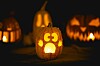 Lysende utskåret gresskar i forgrunnen med flere Halloween-gresskar i bakgrunnen.