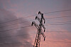 Høyspentmast med kraftlinjer mot en rosa og blå kveldshimmel.